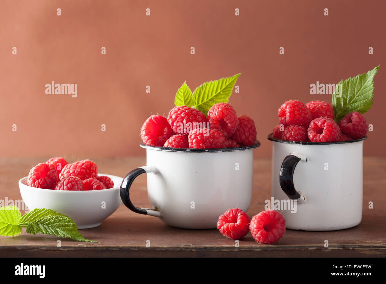 Tasses en émail framboise fraîche sur fond de bois Banque D'Images