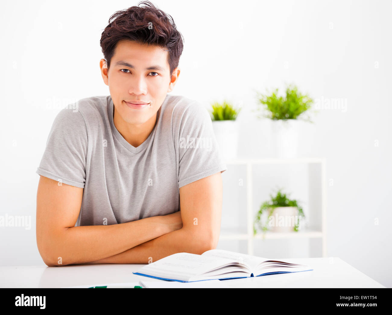 Smiling relaxed young man reading book in living room Banque D'Images