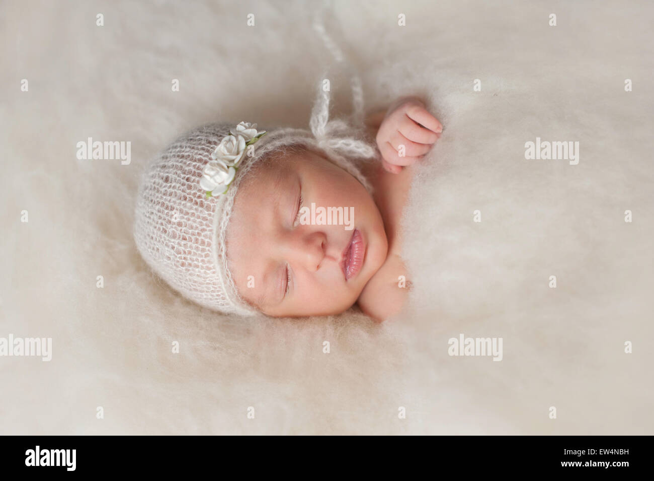 Un portrait d'un beau nouveau-né âgé de sept jours baby girl wearing a white, en mohair, bonnet et bandeau rose. Elle est slee Banque D'Images