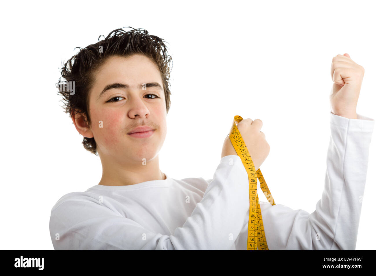 Handsome boy en blanc manches longues T-shirt sourit tout en mesurant le muscle de son bras gauche avec ruban mètre jaune Banque D'Images