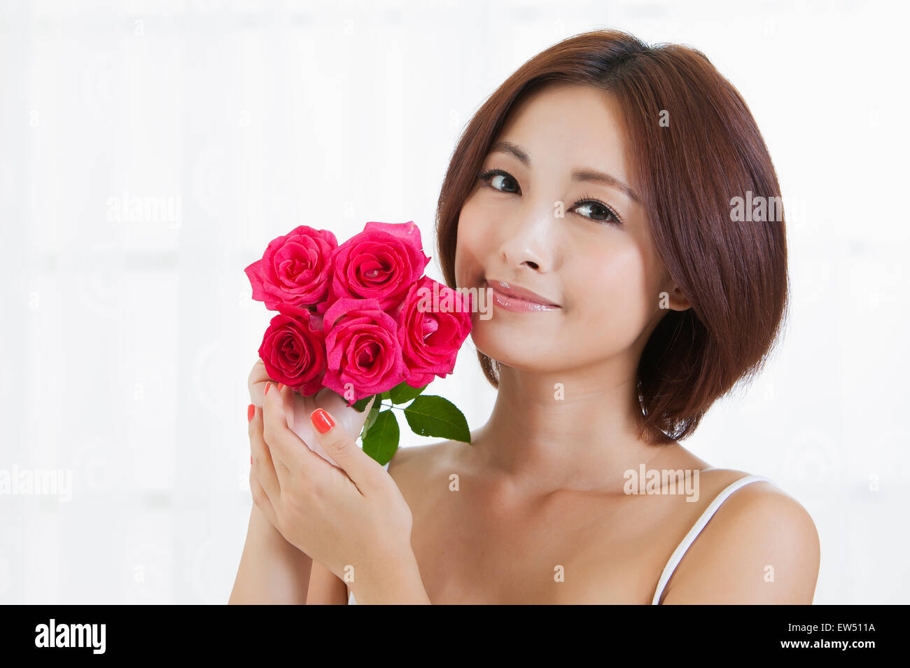 Jeune femme tenant des fleurs et smiling at the camera Banque D'Images