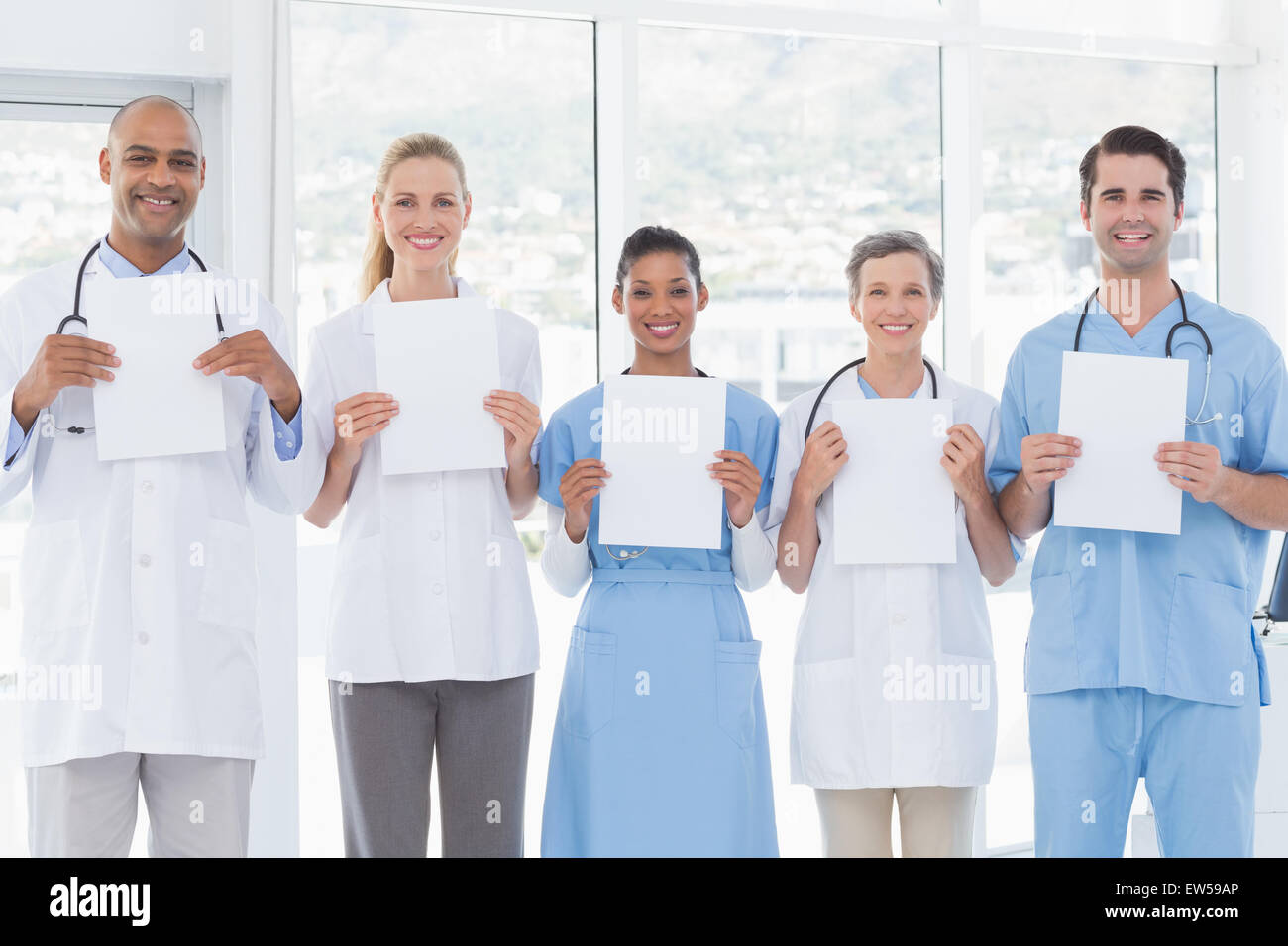 Équipe de smiling doctors looking at camera et holding paper Banque D'Images