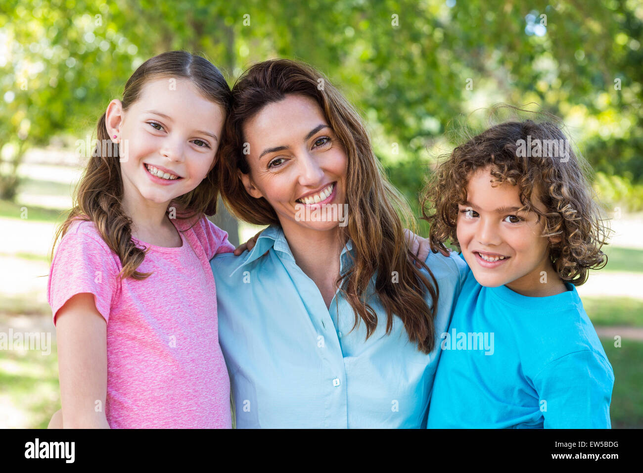 Mère et enfants sourire et s'embrasser dans un parc Banque D'Images