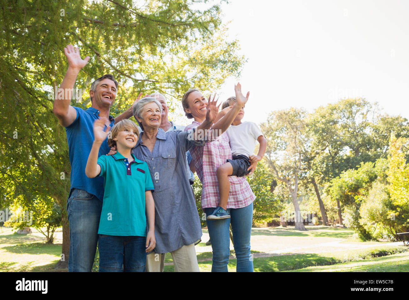 Famille heureuse des signes avec la main dans le parc Banque D'Images