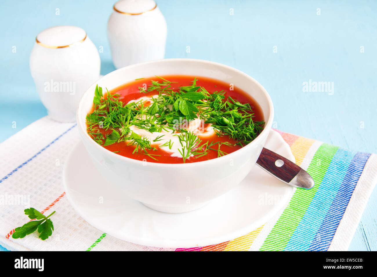 Soupe froide de tomates faites maison avec du fromage à la crème et fines herbes sur table en bois bleu Banque D'Images