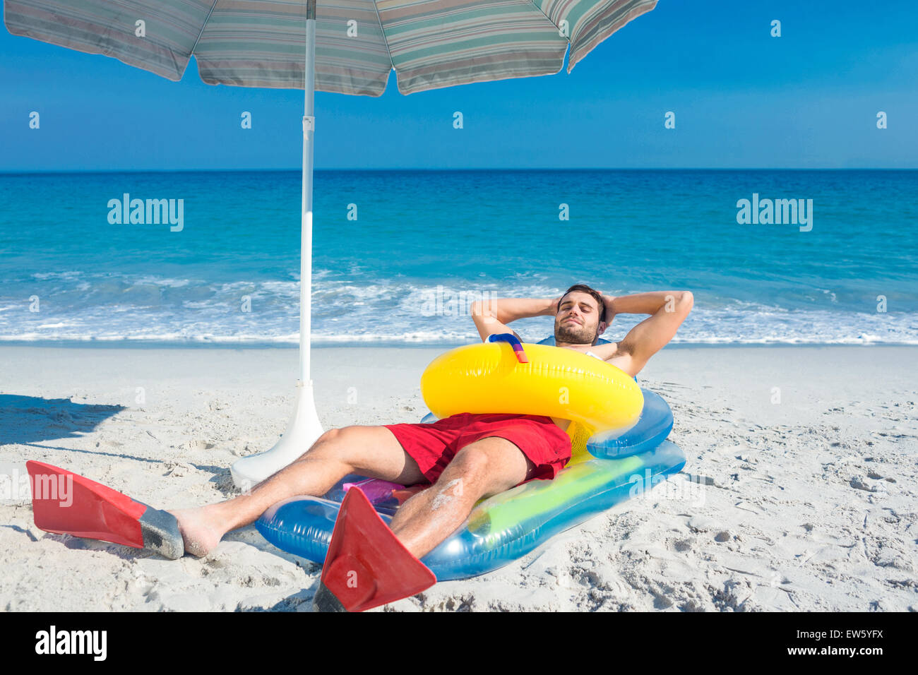 L'homme allongé sur la plage avec palmes et bague en caoutchouc Banque D'Images