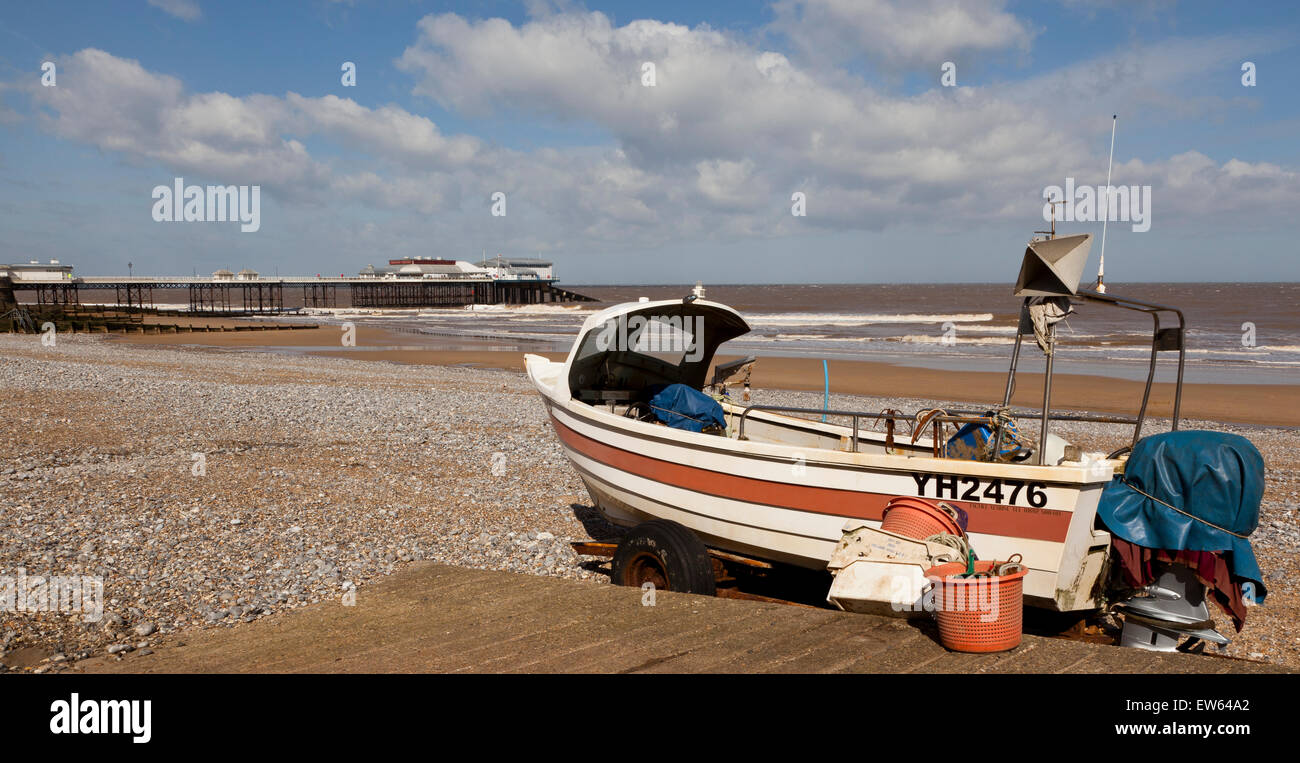 Un bateau de pêche sur la plage de Cromer, Norfolk, Angleterre, Royaume-Uni, avec la mer et de la jetée à l'arrière-plan Banque D'Images