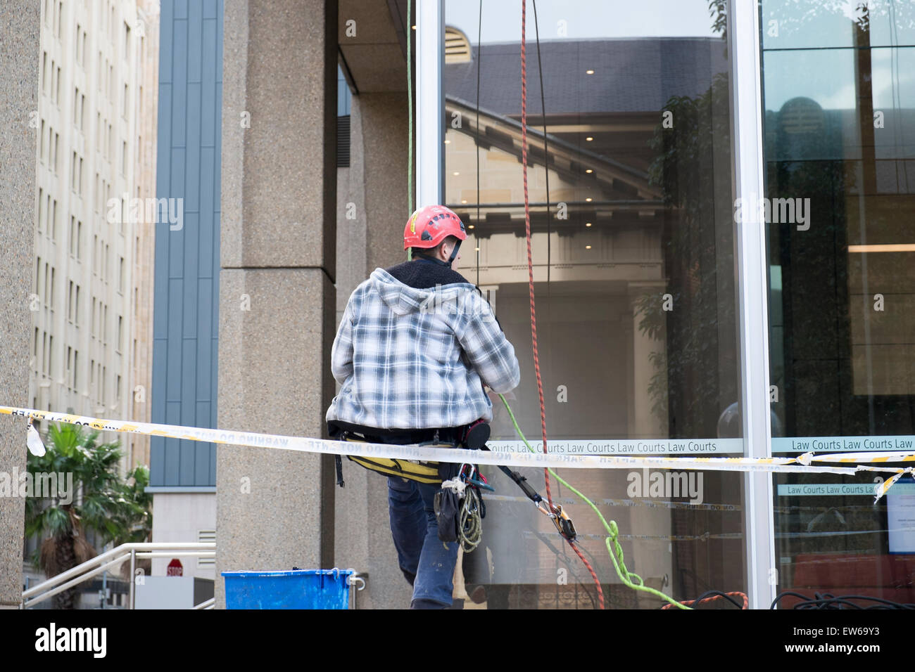 Jeune homme atteint le sol de son poste de responsable de nettoyant de façade extérieure Sydney law courts, de l'Australie Banque D'Images