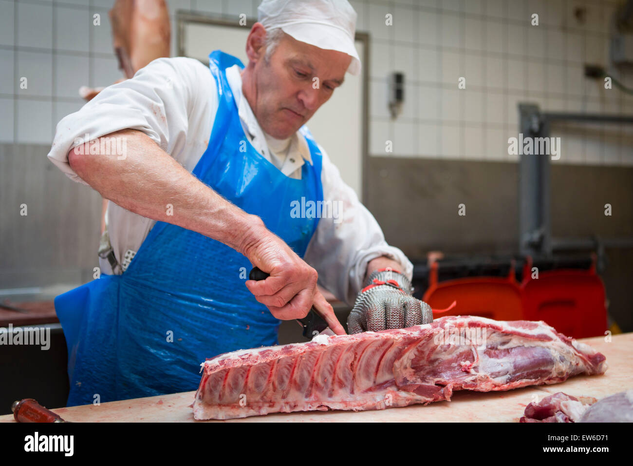 Boucher au travail à la boucherie de porc coupe Banque D'Images