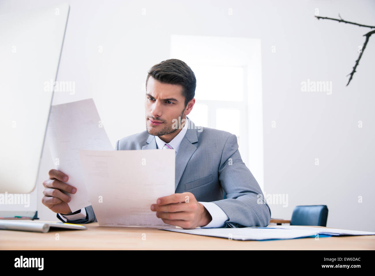 Confident businessman reading papers sur son lieu de travail à Office Banque D'Images