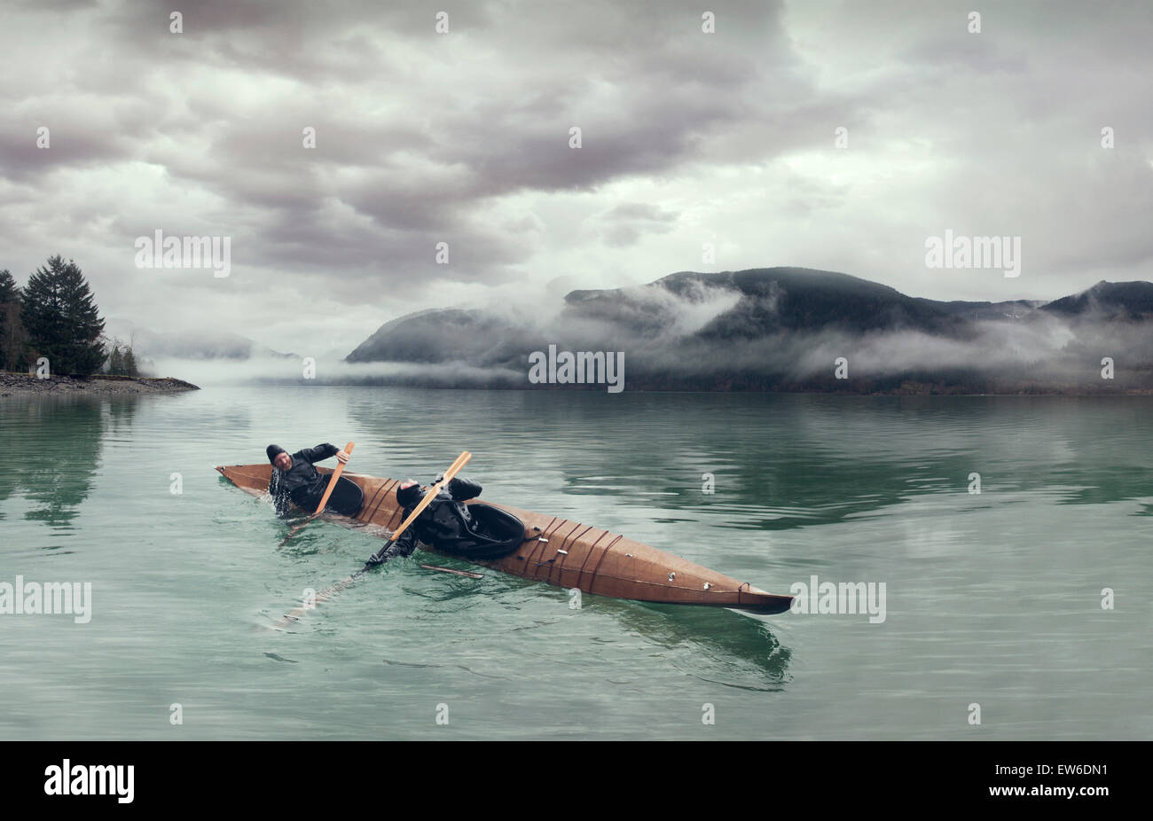 Deux kayakistes faire un double rouleau dans un skin-on-frame kayak sur le Puget Sound. Banque D'Images