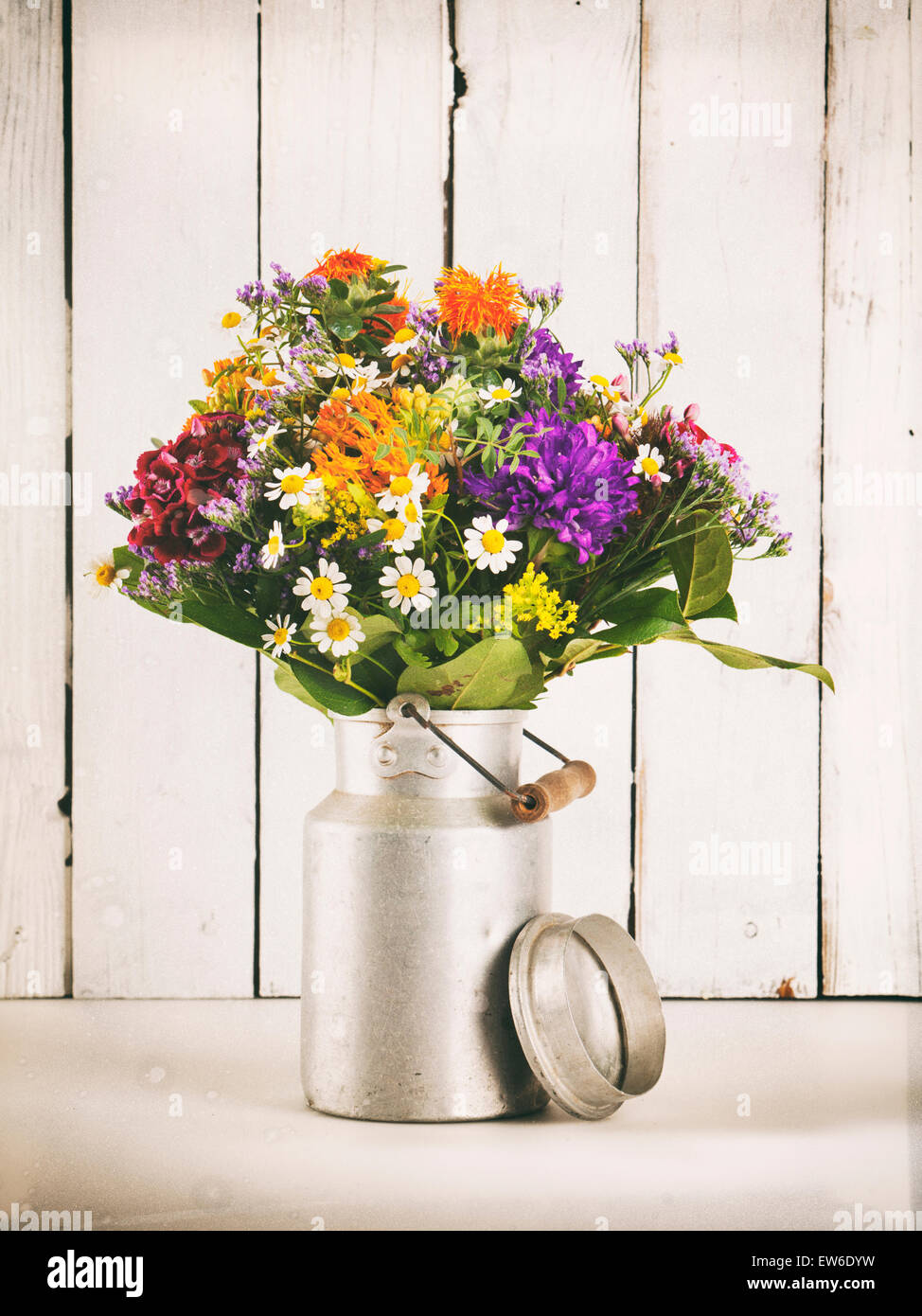 Bouquet de fleurs d'été dans le vieux bidon de lait en face du mur en bois rustique, traitement vintage Banque D'Images