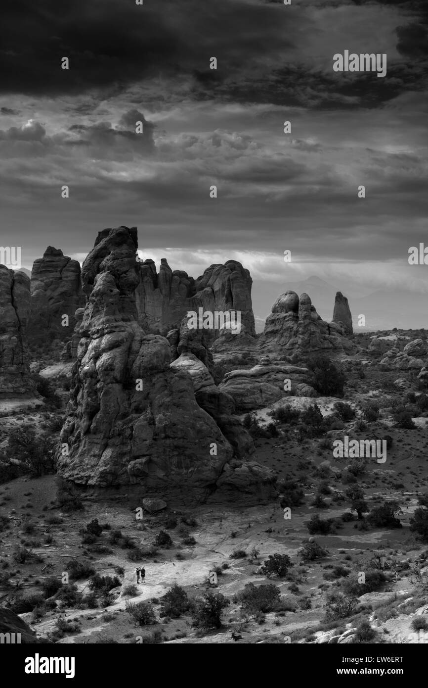 Deux randonneurs sont éclipsées par les formations de roche géant d'Arches National Park, Utah. Banque D'Images