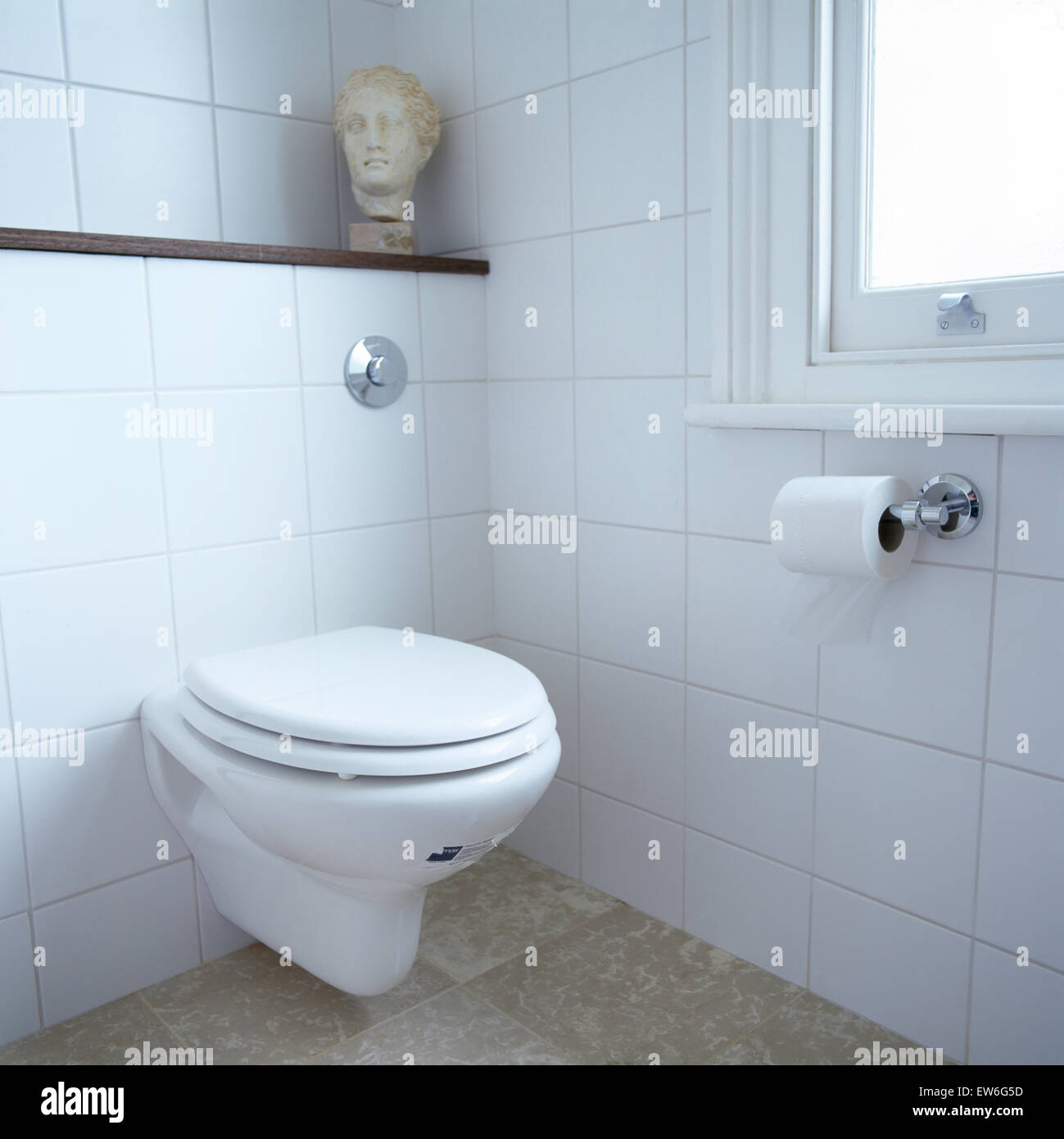 La sculpture classique tête sur étagère au-dessus de toilettes dans salle de bains carrelée de blanc Banque D'Images