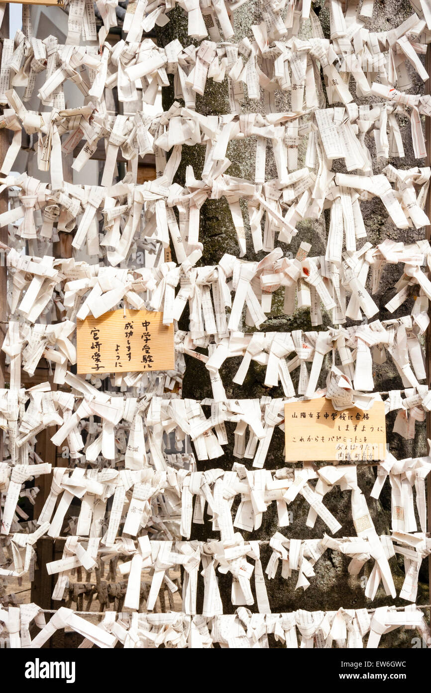 Japon, Kurashiki, Sanctuaire D'Achi-Jinja. Cadre en bois avec rangées d'omikuji, feuilles de papier blanc de fortune et deux comprimés en bois souhaitant l'ema attaché sur. Banque D'Images