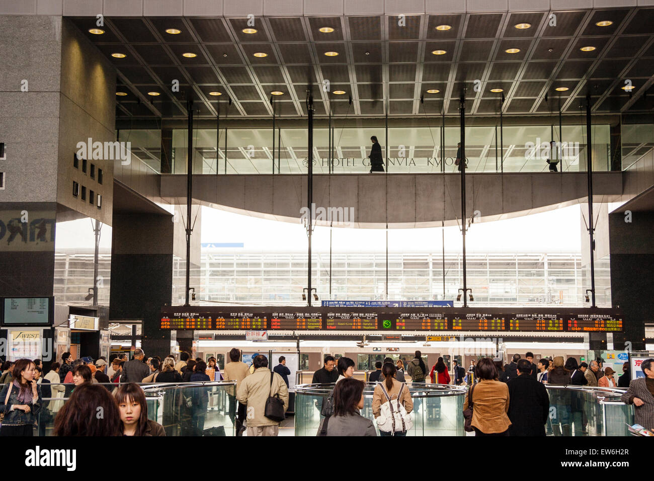 La gare de Kyoto, conçue par Hiroshi Hara, entrée occupée et barrière de ticker aux plates-formes avec les temps de train en hauteur affichent des informations et une passerelle. Banque D'Images