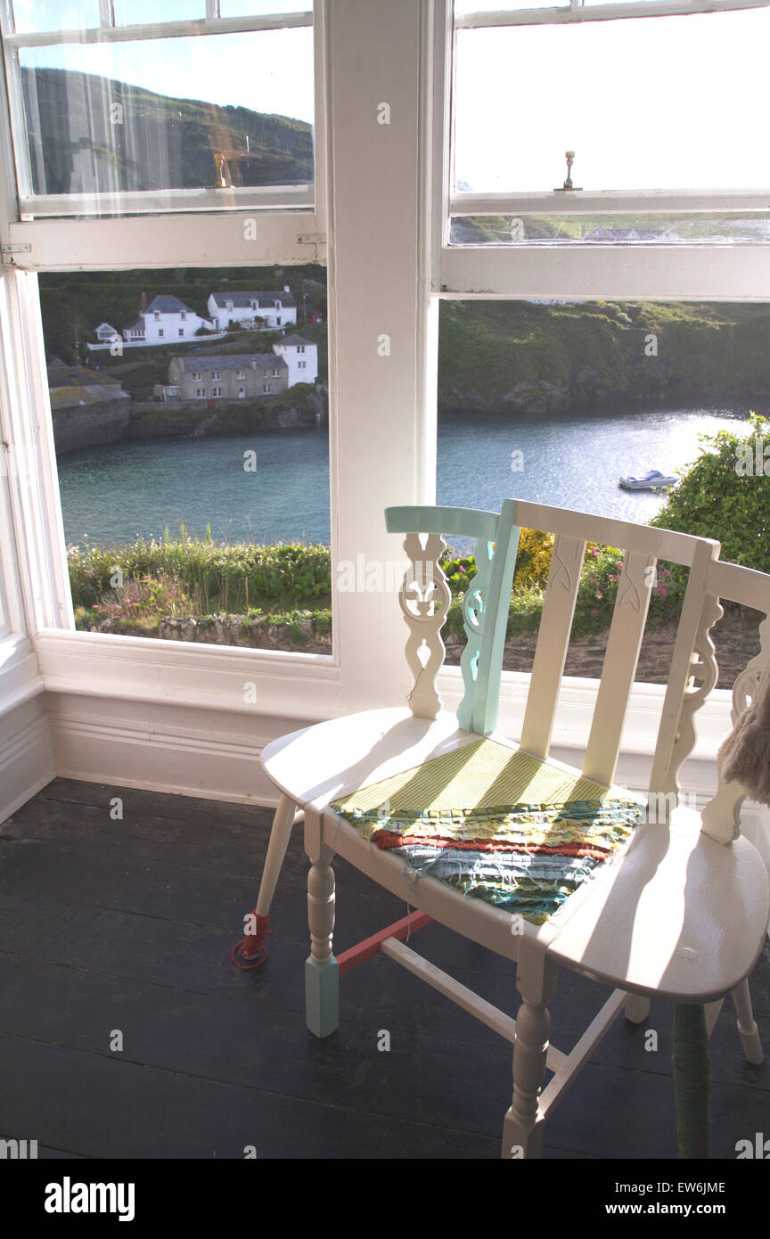 Nouveauté peint chaise à côté des fenêtres à guillotine ouverte avec vue sur Port Isaac à Cornwall Banque D'Images