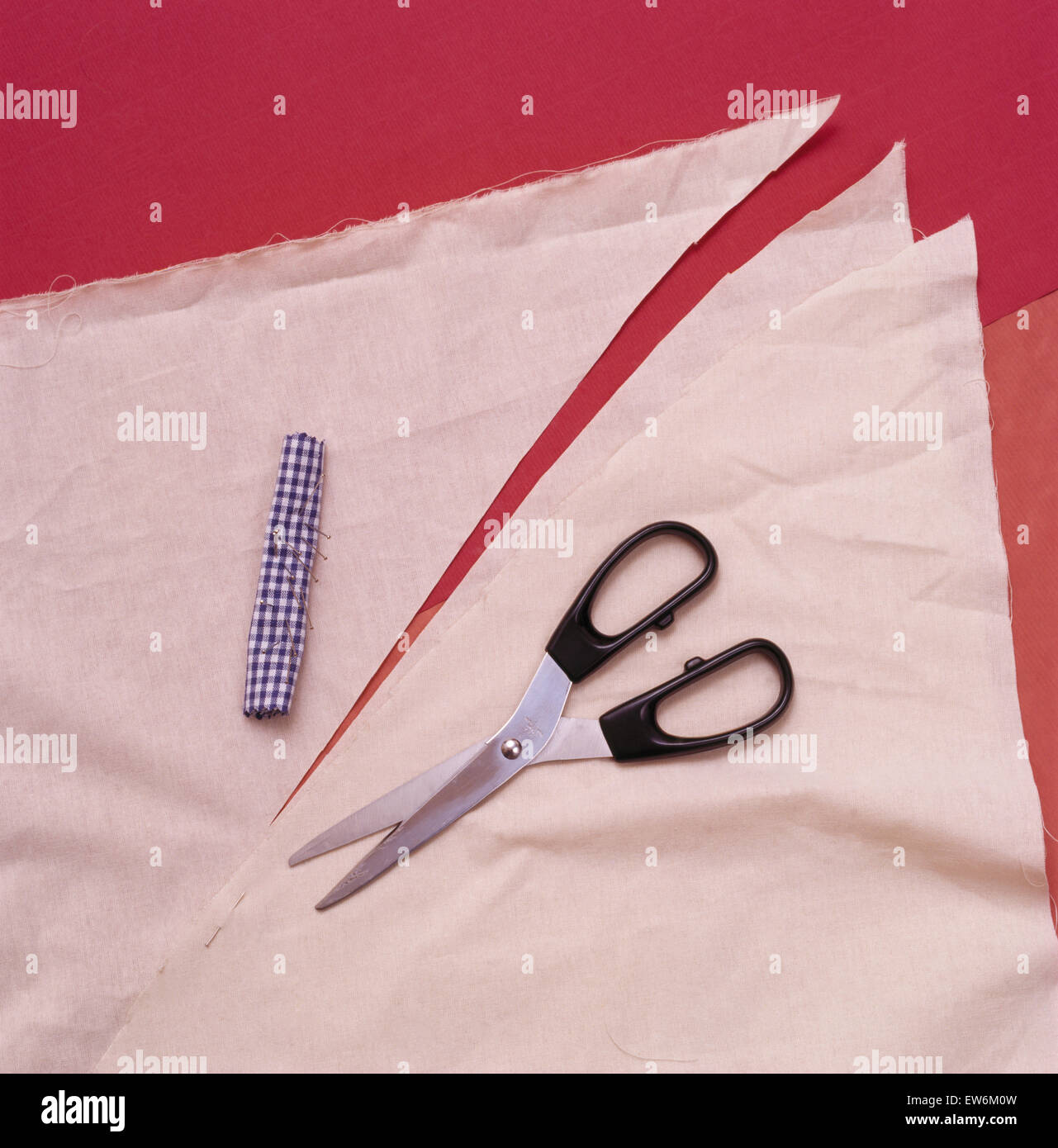 Close-up d'un motif de papier et des ciseaux pour faire une étole de velours rouge bordée de soie rose fuchsia Banque D'Images