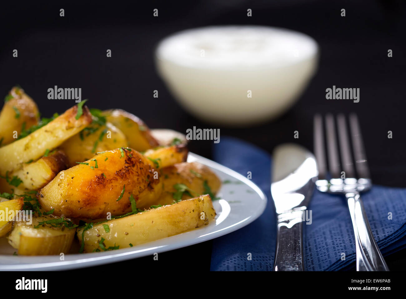 Les pommes de terre cuites au four avec du persil sur une assiette avec une fourchette et couteau Banque D'Images