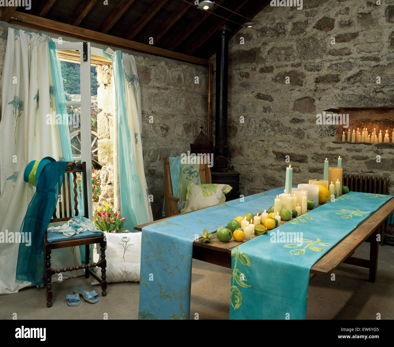 Tableau peint à la main sur une table à manger avec des rideaux de coordination sur la vitre dans une grange en pierre Banque D'Images