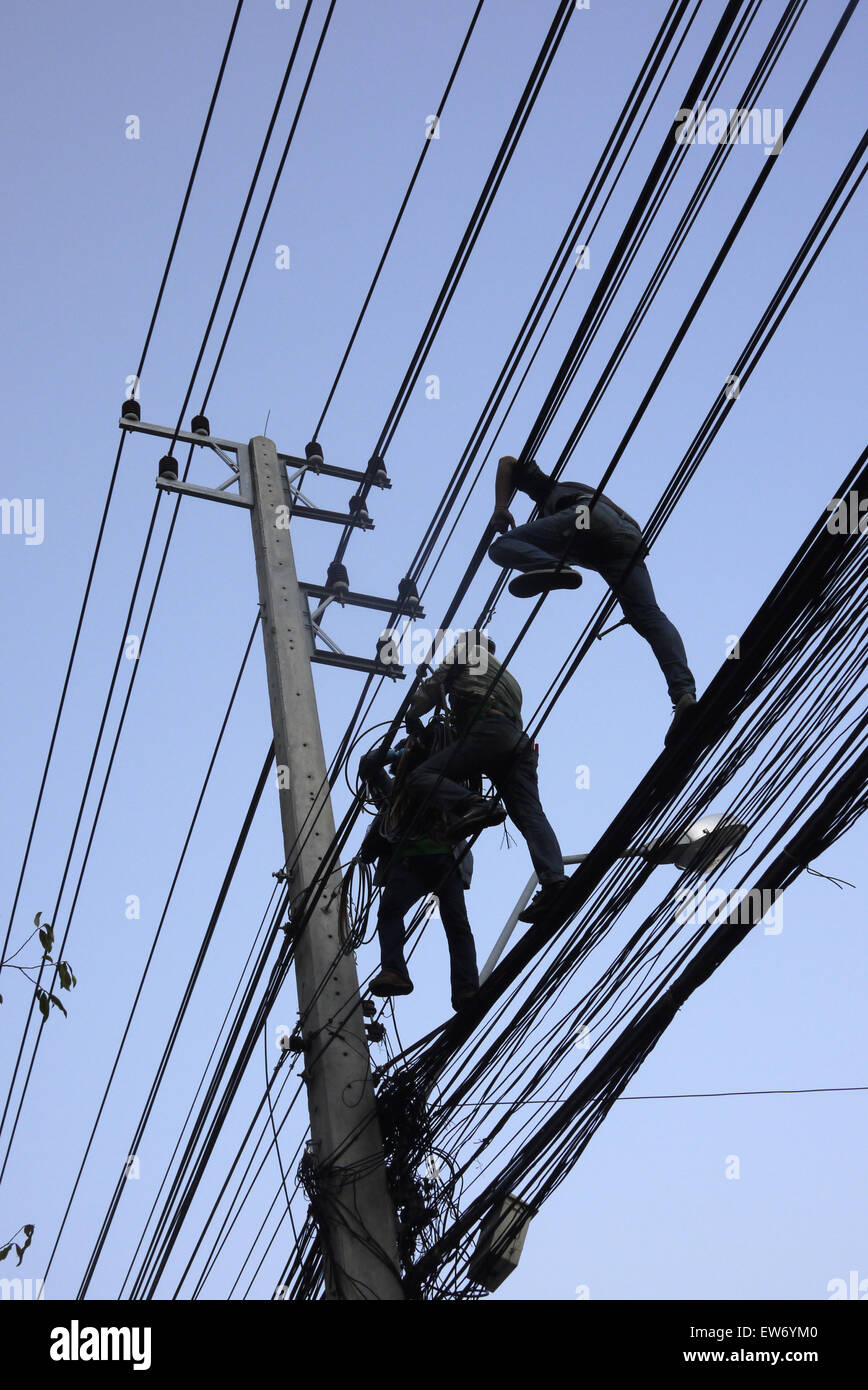 Les monteurs de câbles électriques travaillant dans une situation dangereuse au-dessus d'une rue de ville à Pattaya en Thaïlande Banque D'Images