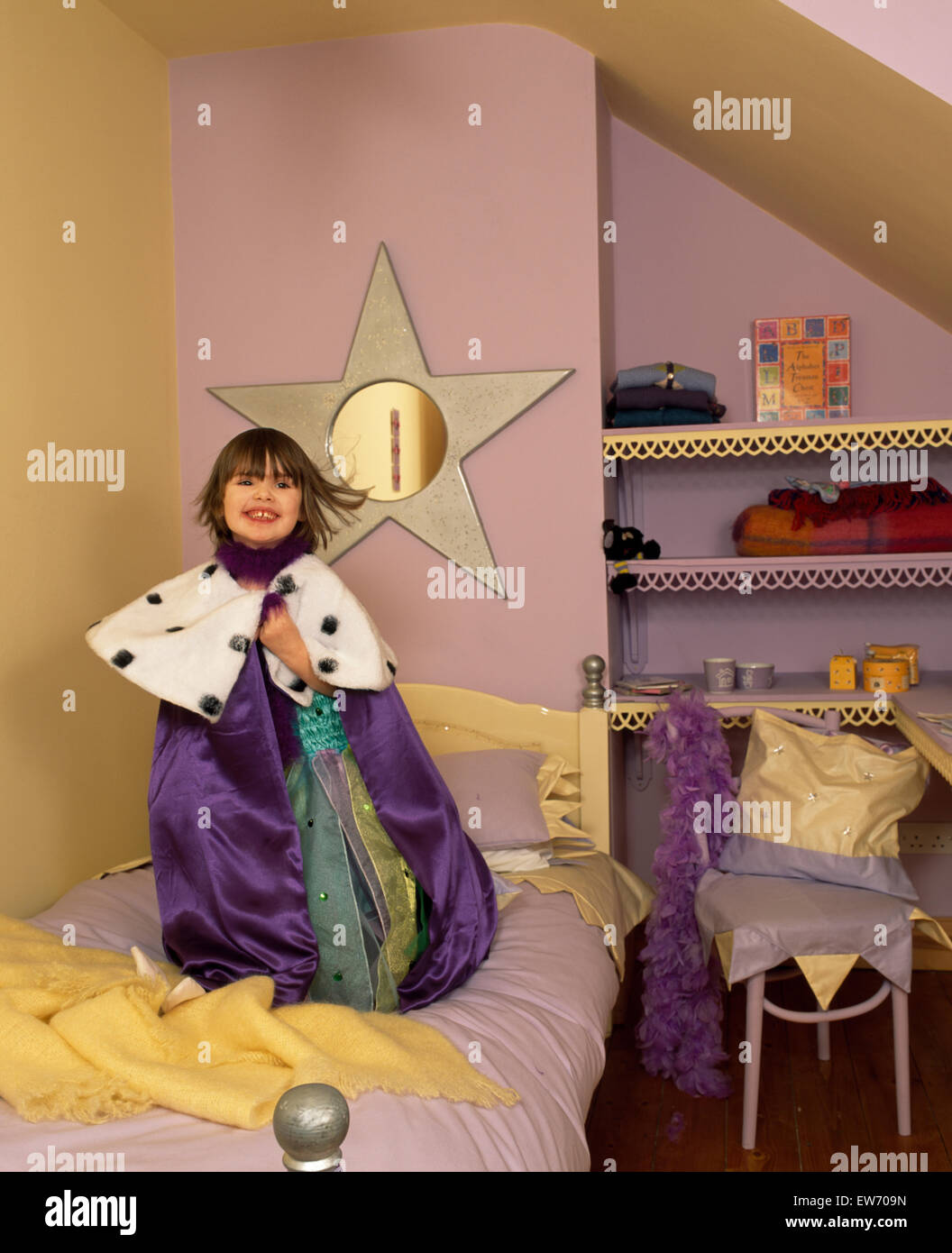 Portrait d'une petite fille portant un costume de Fairy Queen et debout sur le lit dans une chambre à thème star POUR LA RÉDACTION Banque D'Images
