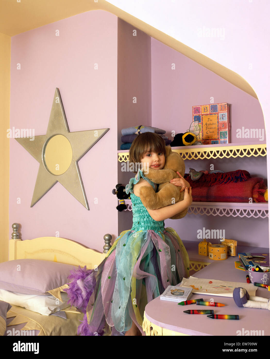 Portrait d'une petite fille portant un costume de fée et de câliner un ours dans une chambre à thème star POUR UN USAGE ÉDITORIAL SUR Banque D'Images
