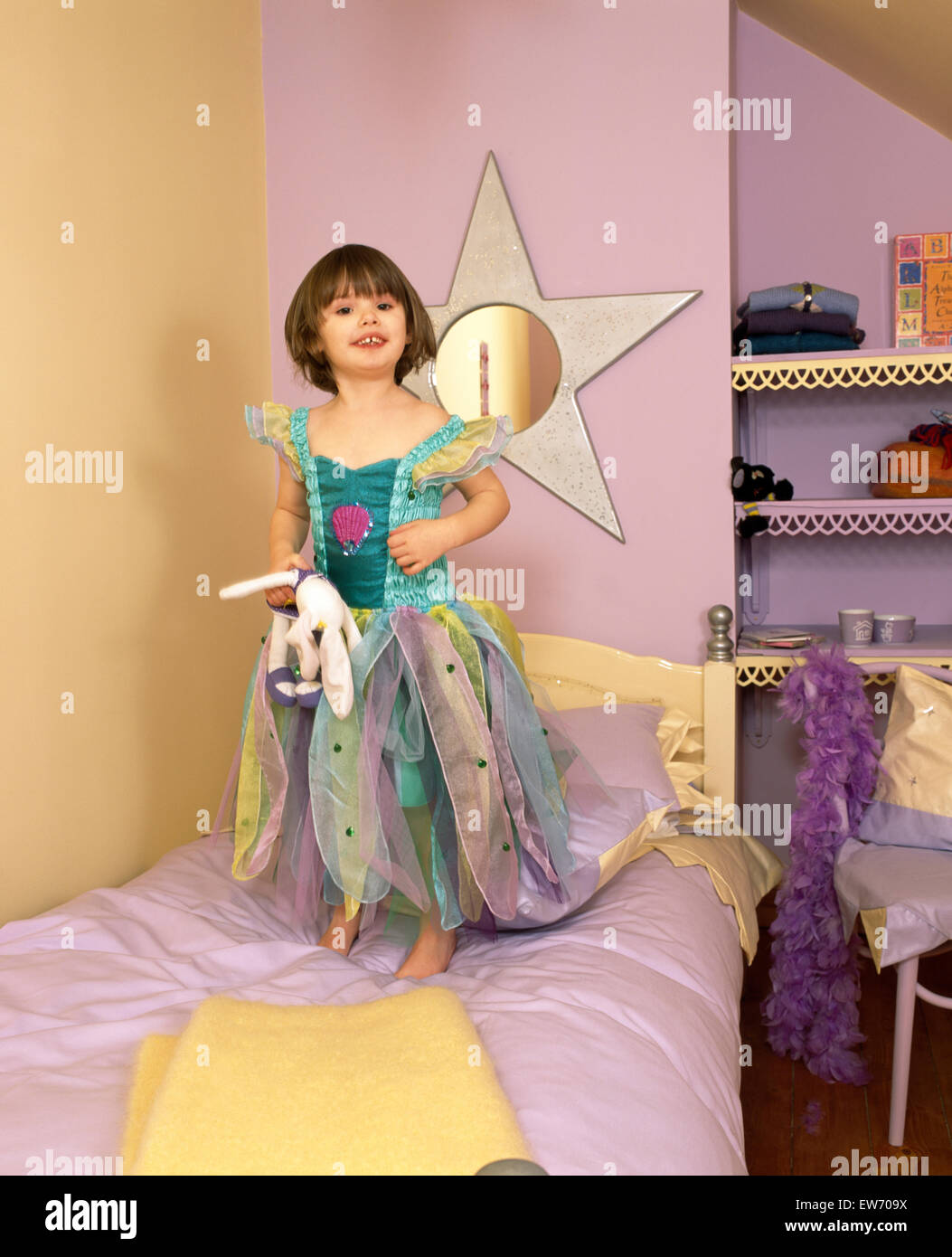 Portrait d'une petite fille portant un costume fée debout sur le lit dans une chambre à thème star pour un usage éditorial uniquement Banque D'Images