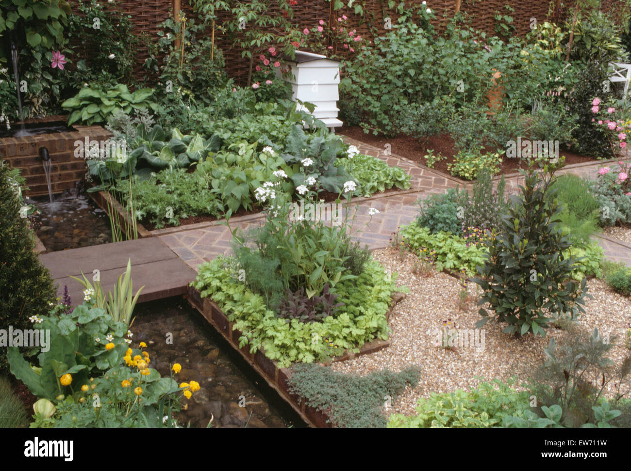 Petite piscine rectangulaire et un blanc dans une ruche d'herbe bien approvisionné et un potager avec des sentiers asphaltés Banque D'Images