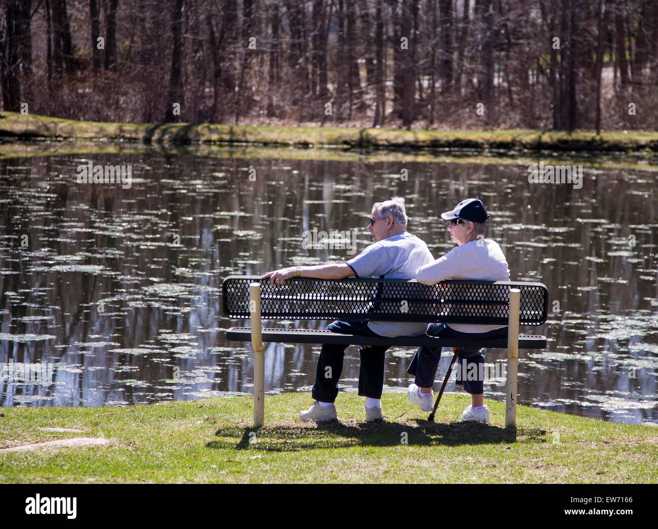 Vieux couple assis sur un banc à côté d'un étang Banque D'Images