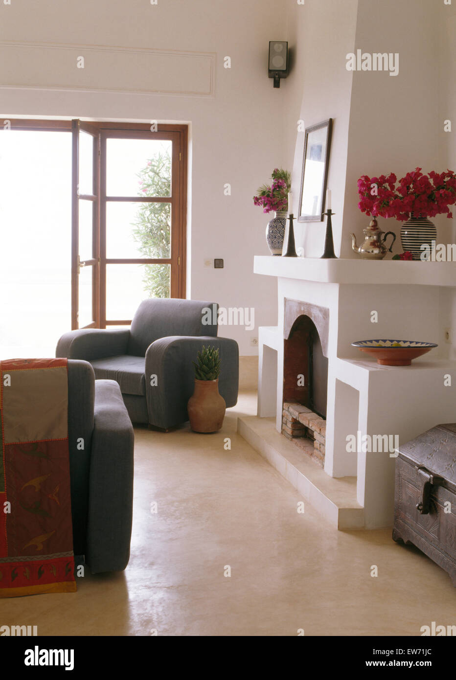 Meubles gris côtière marocaine au salon avec cheminée et blanc plancher de béton poli Banque D'Images