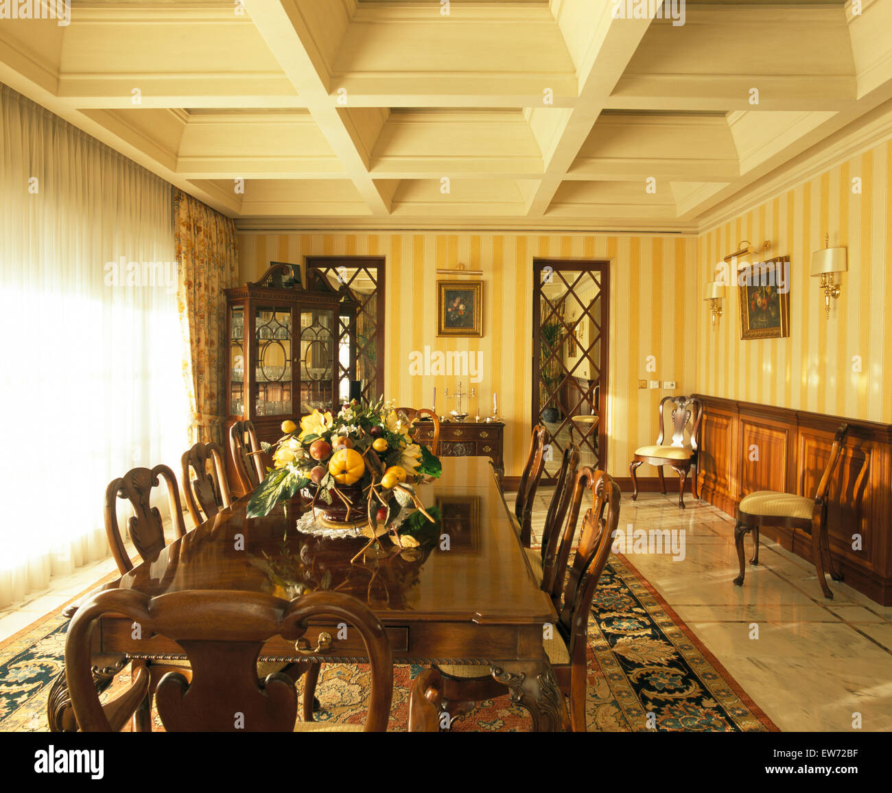 Table et chaises en bois foncé en espagnol salle à manger avec papier peint  à rayures jaune Photo Stock - Alamy