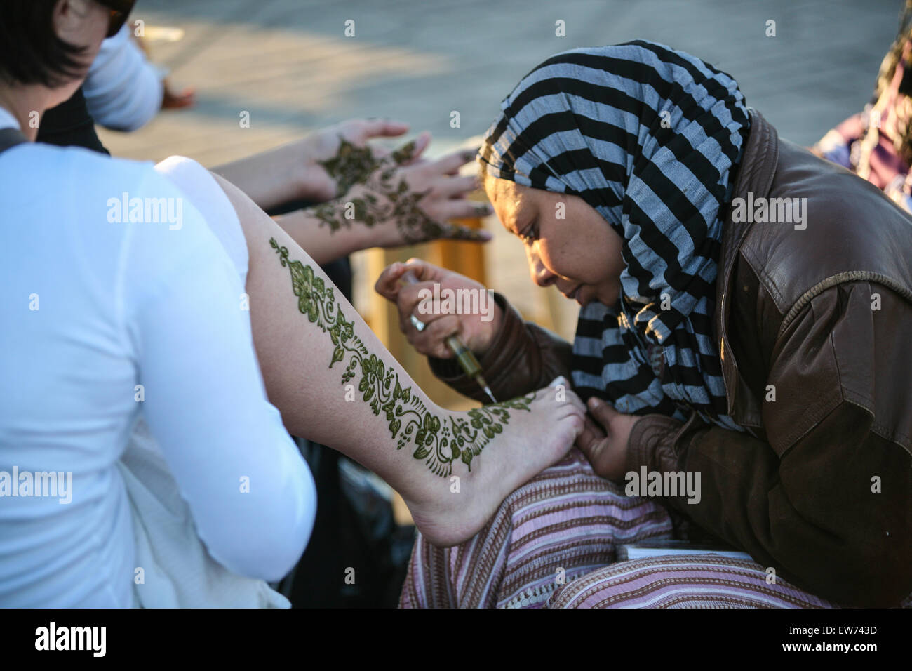 Tourisme,femme, ayant mis au henné sur leurs jambes,mains,tattoo,square ,Djemaa Djemma el Fna,au coucher du soleil.Dans le centre de Marrakech, Marrakech, Maroc, Afrique. Banque D'Images