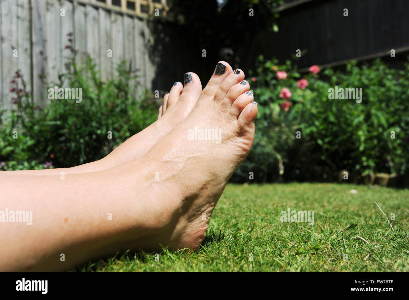 Santé et beauté femme aux ongles glitter peint pour l'été le soleil en jardin Banque D'Images