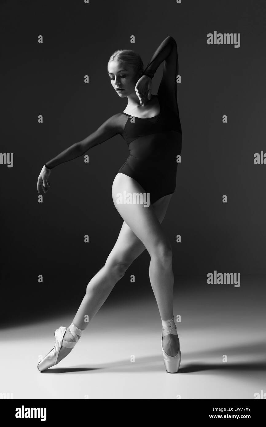 Jeune belle danseuse style moderne posant sur un fond gris studio photo noir et blanc. Banque D'Images