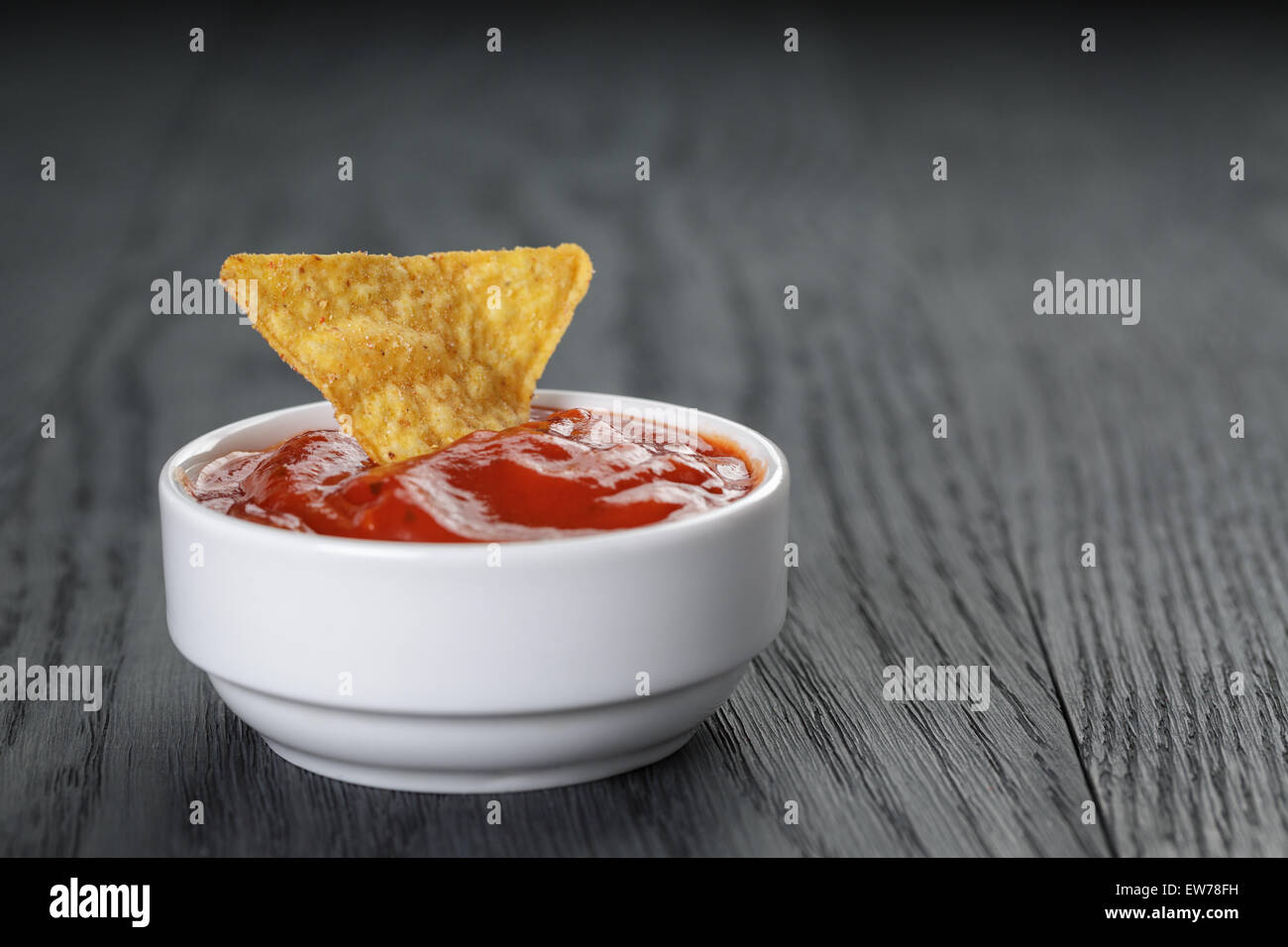 Tortilla chip dans un bol avec la sauce tomate sur la table en bois Banque D'Images