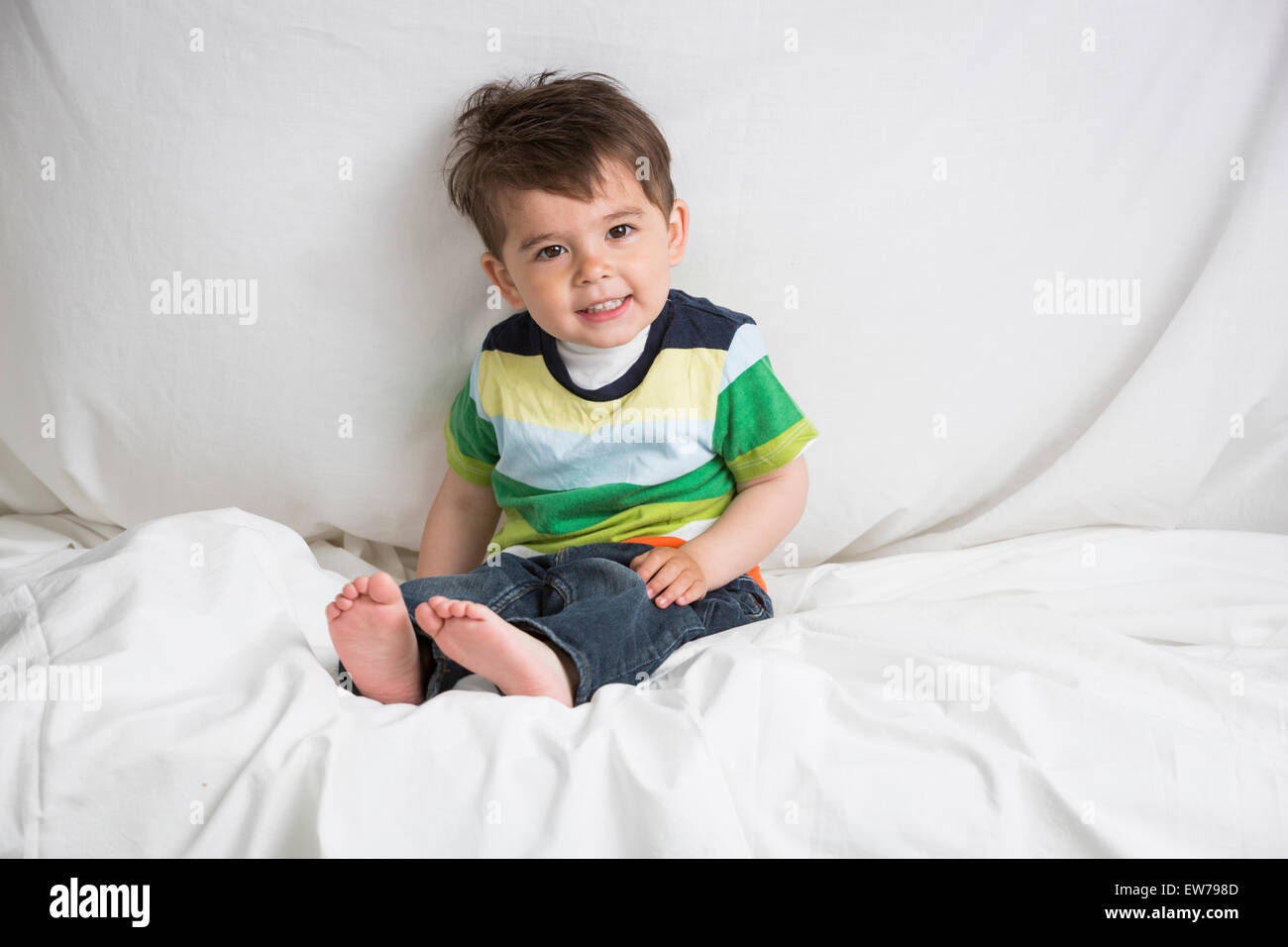 Petit garçon assis sur un lit Banque D'Images