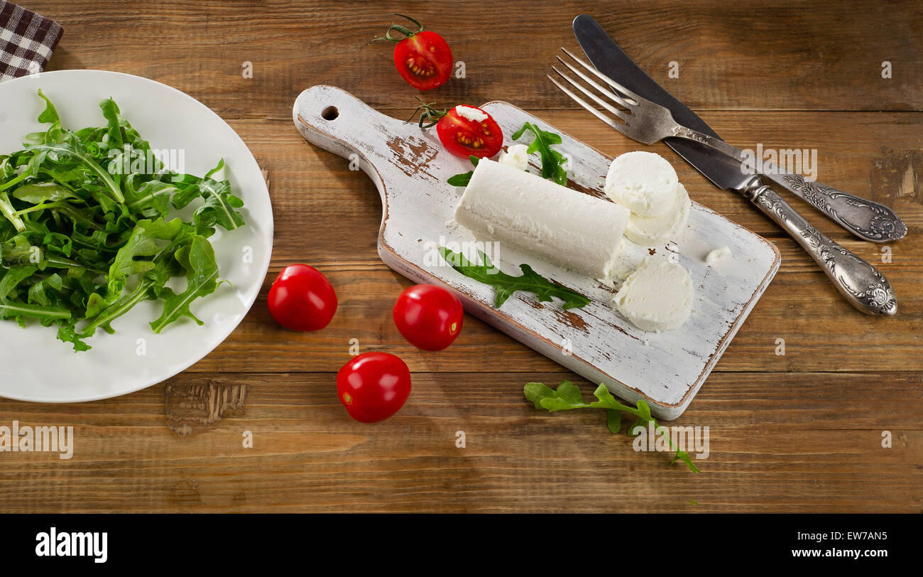 Le fromage de chèvre avec une salade fraîche et des tomates sur une vieille table en bois. Banque D'Images