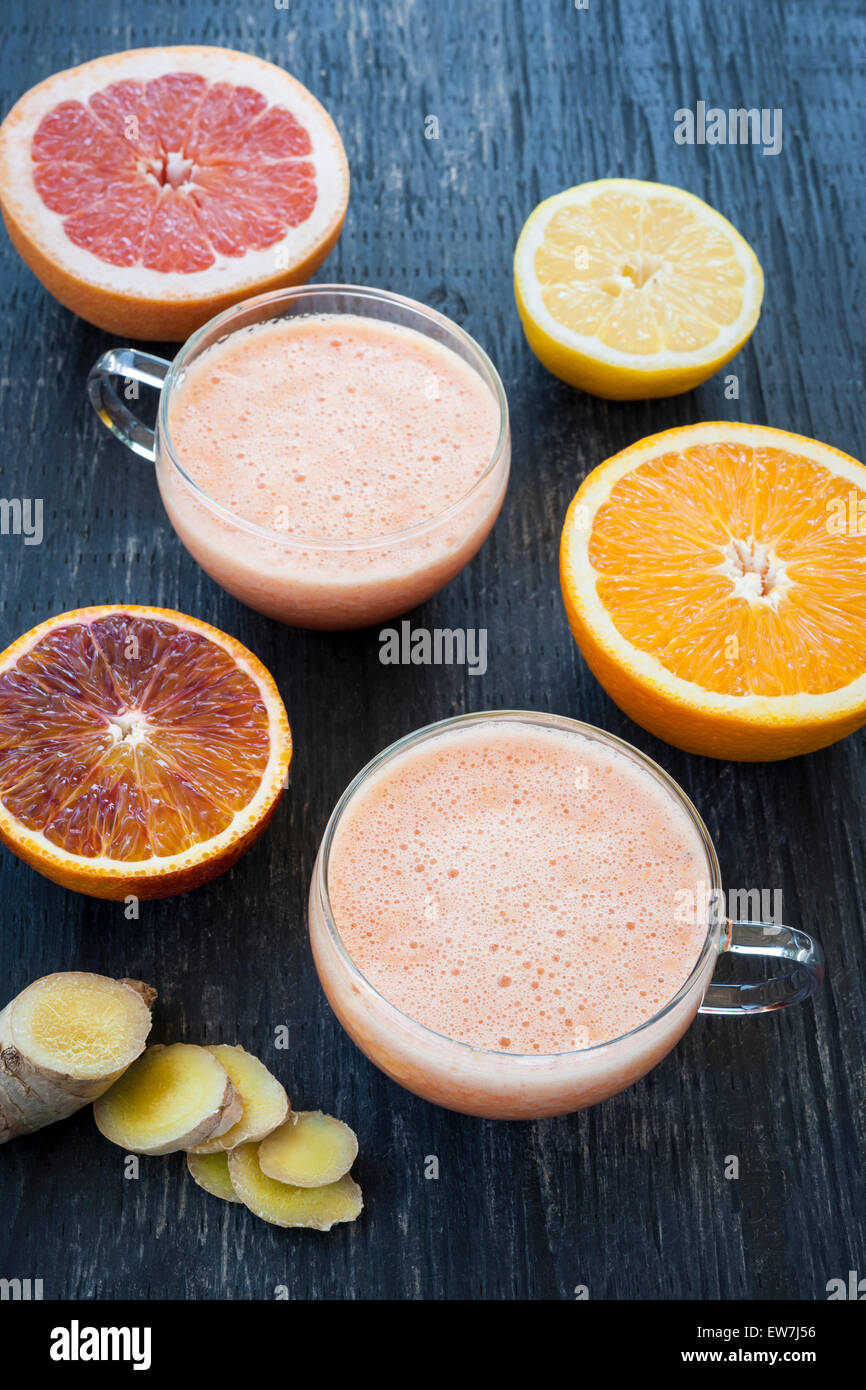 Les agrumes frais et le gingembre smoothies avec tranches de fruits sur fond de bois rustique, vue d'en haut Banque D'Images