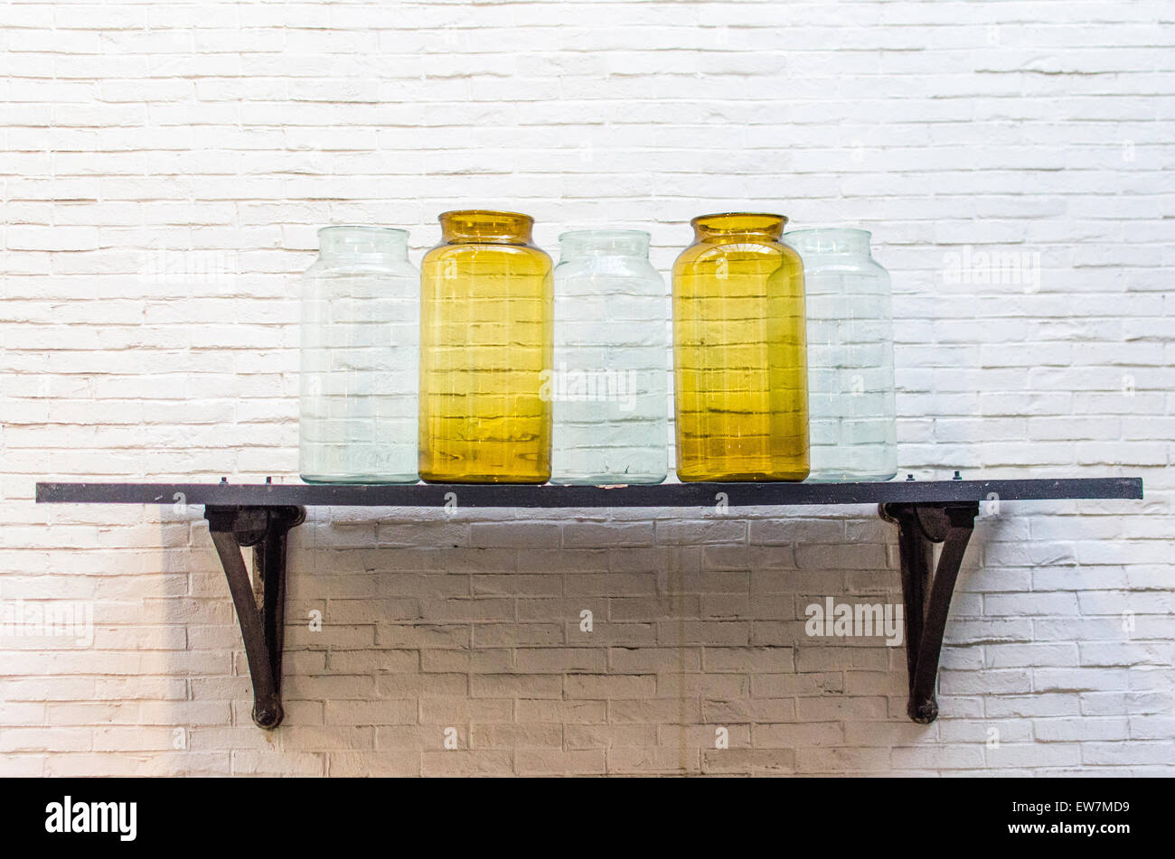 Cinq vases en cristal transparent et jaune sur une raquette noir Banque D'Images