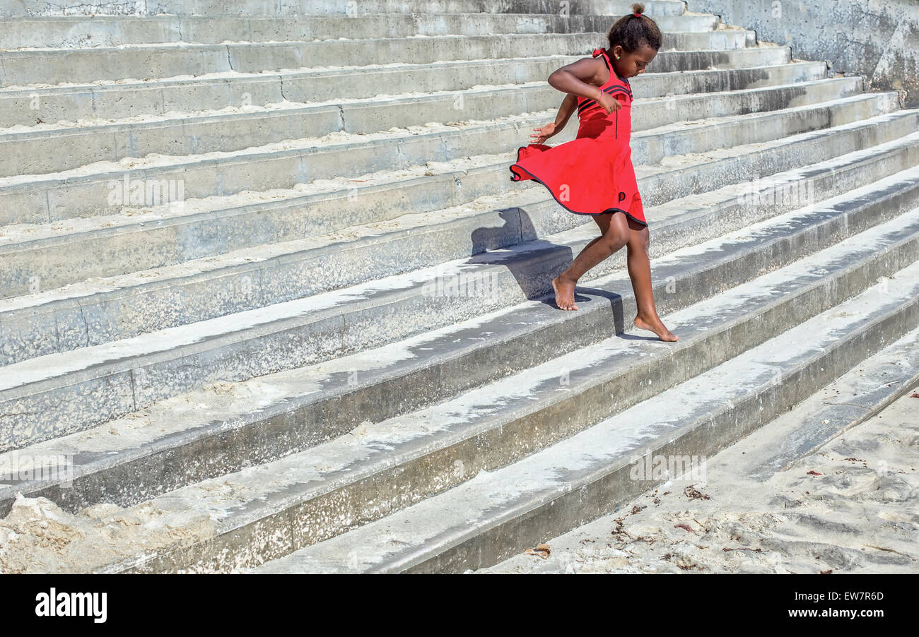 Jeune fille dans une robe rouge fonctionnant en bas comme suit Banque D'Images