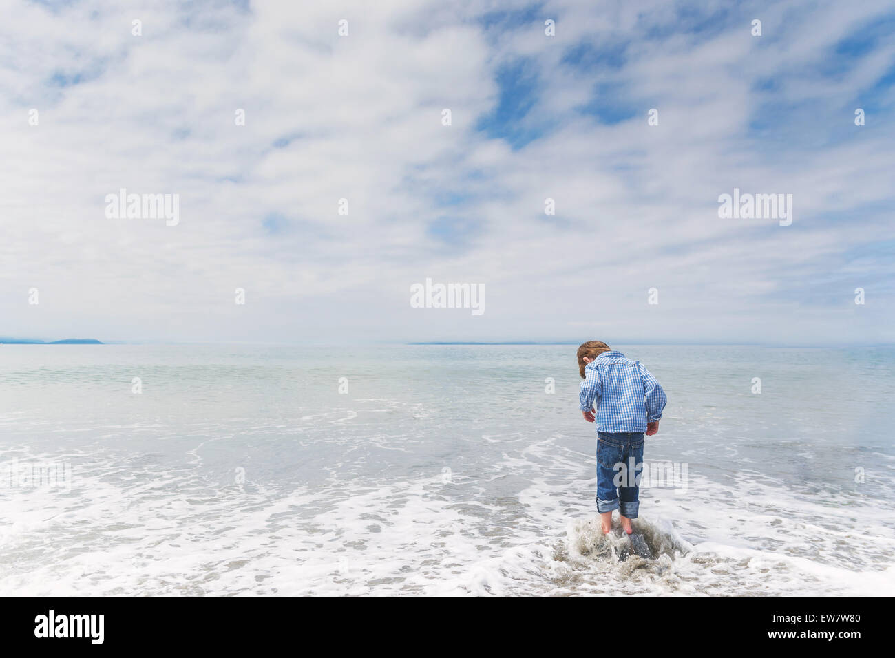 Vue arrière d'un garçon debout sur un rocher dans la mer Banque D'Images