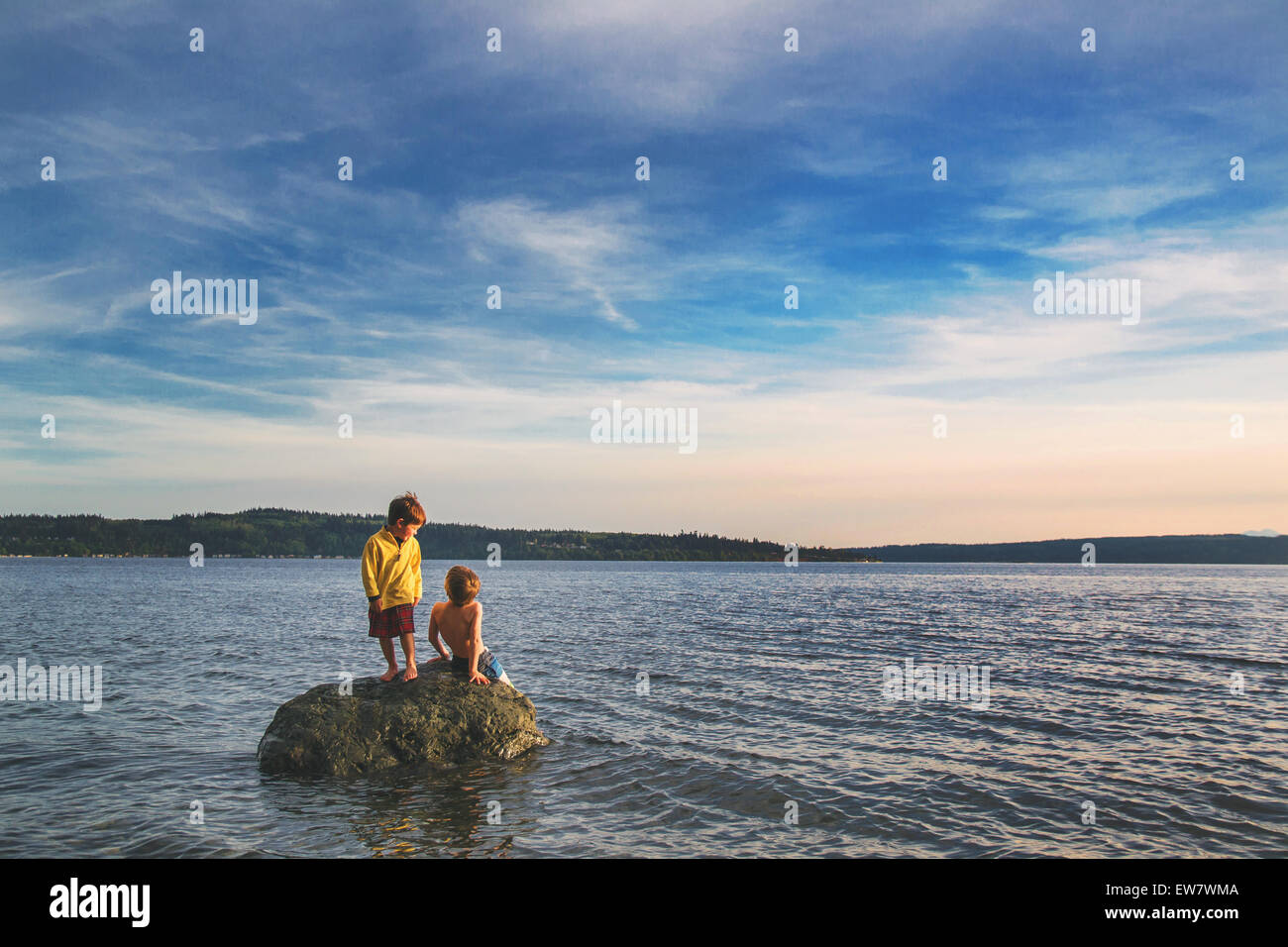Deux garçons assis sur un rocher dans la mer Banque D'Images