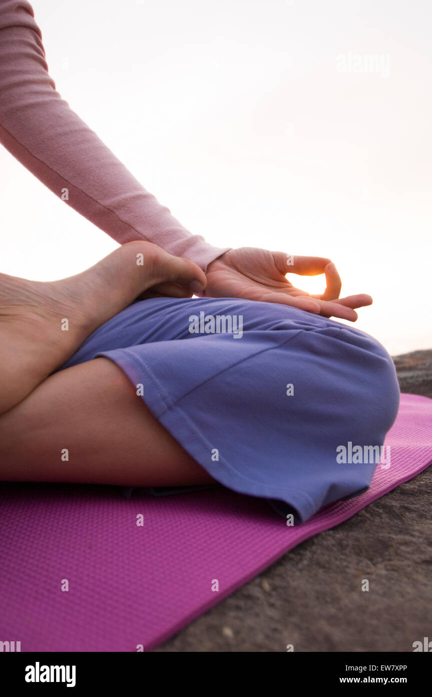 Une femme pratiquant le yoga sur un éperon rocheux au-dessus de l'océan Pacifique au nord, l'un de Curl Curl Sydneys Plages du Nord. Banque D'Images