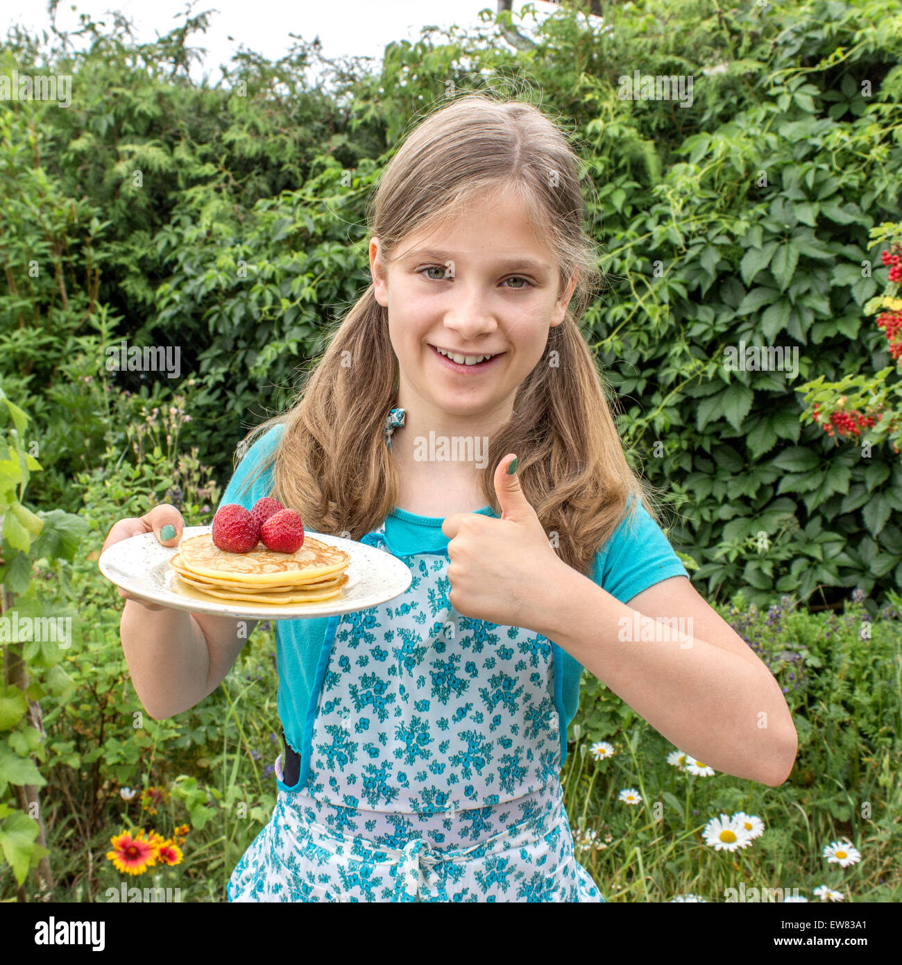 Une jeune fille tenant une assiette de crêpes et de fraises Banque D'Images
