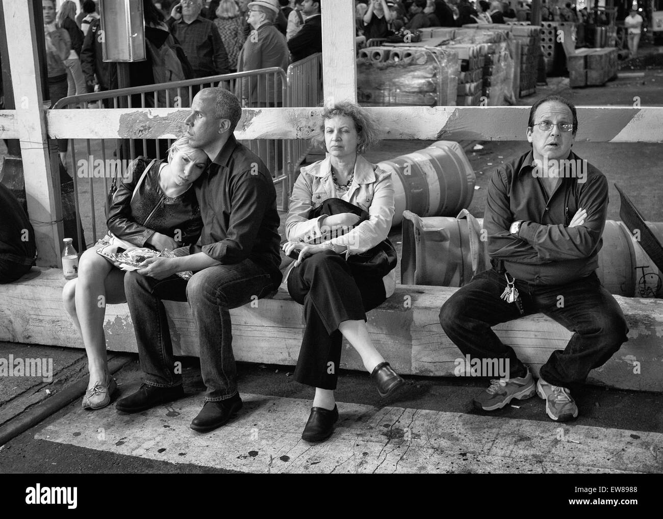 Quatre personnes assis devant un chantier de construction à l'extérieur de New York Penn Station, attendant qu'elle ré-ouvert après la station avait Banque D'Images