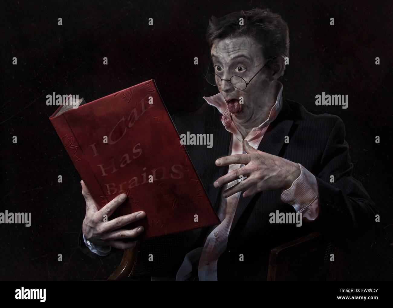 Zombie mâle en train de lire un livre sur un fond sombre. Banque D'Images