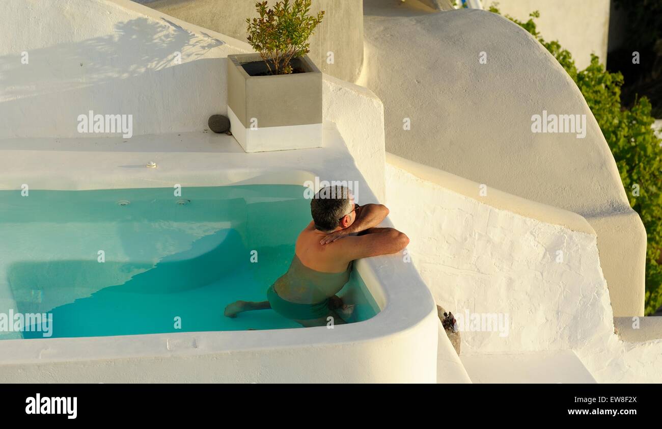 Un homme adulte regardant le coucher de soleil d'une piscine privée Santorini Grèce Banque D'Images