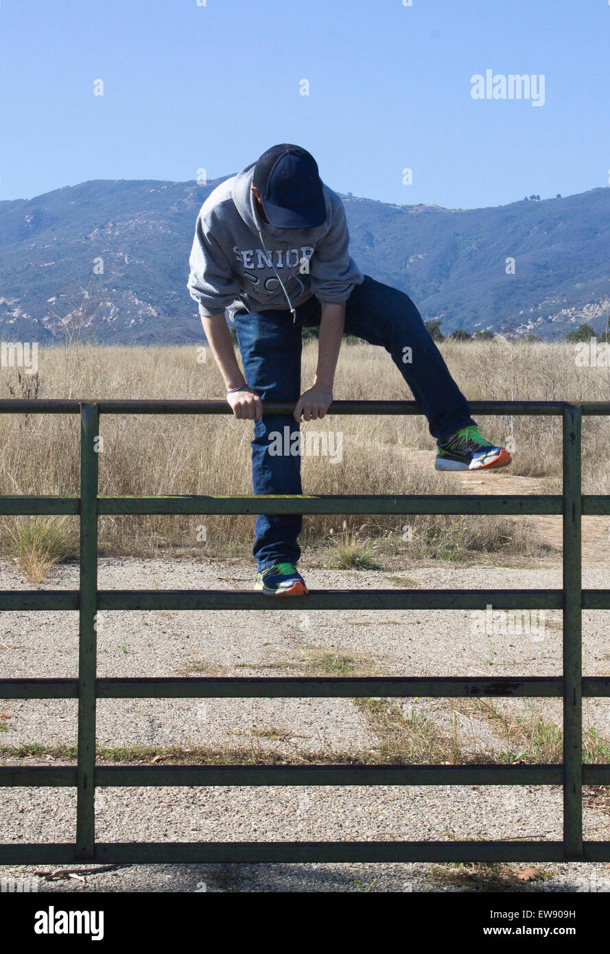 Teen boy climbing fence Banque D'Images