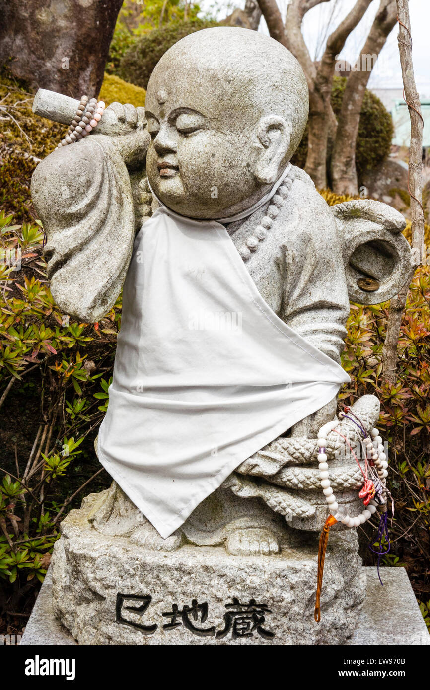 Japon, Miyajima. Temple de Daisho-in. Petite statue en pierre de Jizo d'un moine bouddhiste debout portant un seau avec un serpent enroulé autour d'elle. Banque D'Images